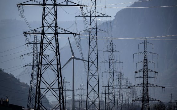 A wind turbine is surrounded by electricity pylons near Evionnaz, Canton of Valais, western Switzerand on March 28, 2022. - (Photo by Fabrice COFFRINI / AFP)