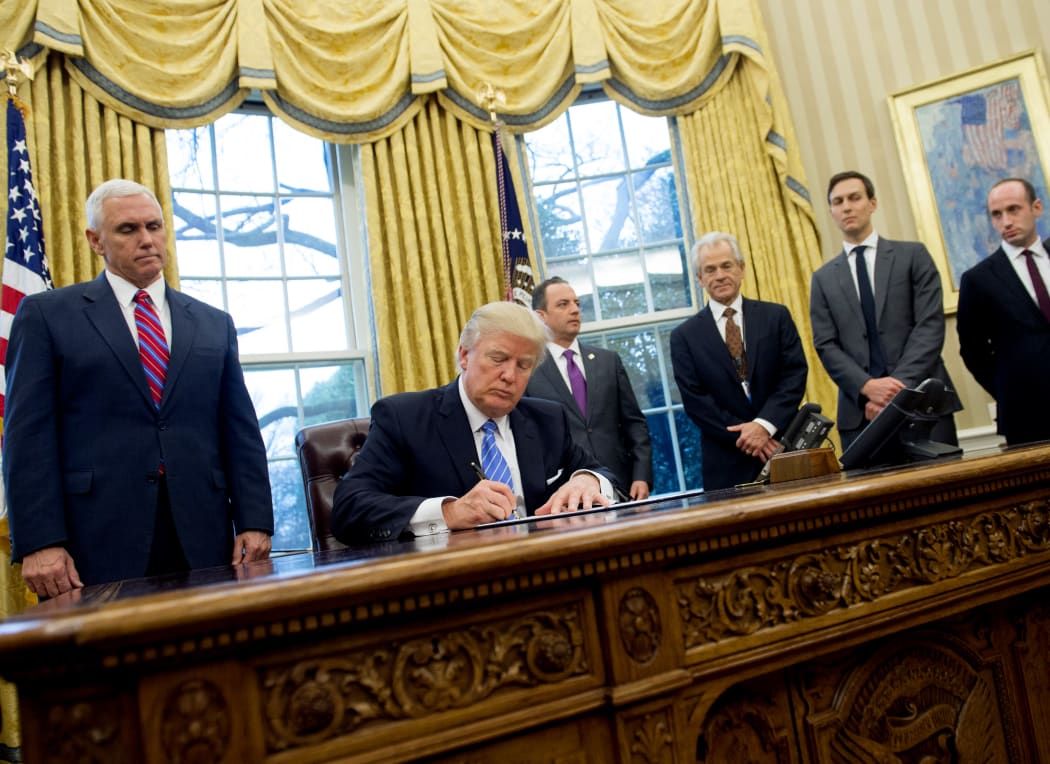 Donald Trump, seated, signed, three executive orders on Monday, including one banning any US-funded organisations from speaking about abortion.