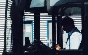 A person sitting in the drivers seat of a bus.