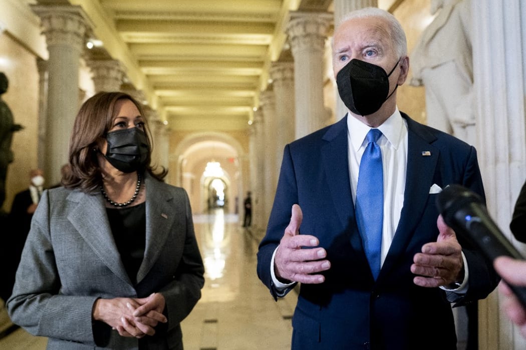 US President Joe Biden speaks to reporters in the Hall of Columns as Vice President Kamala Harris listens following a ceremony on the first anniversary of the deadly insurrection at the US Capitol in Washington, DC, on January 6, 2022.
