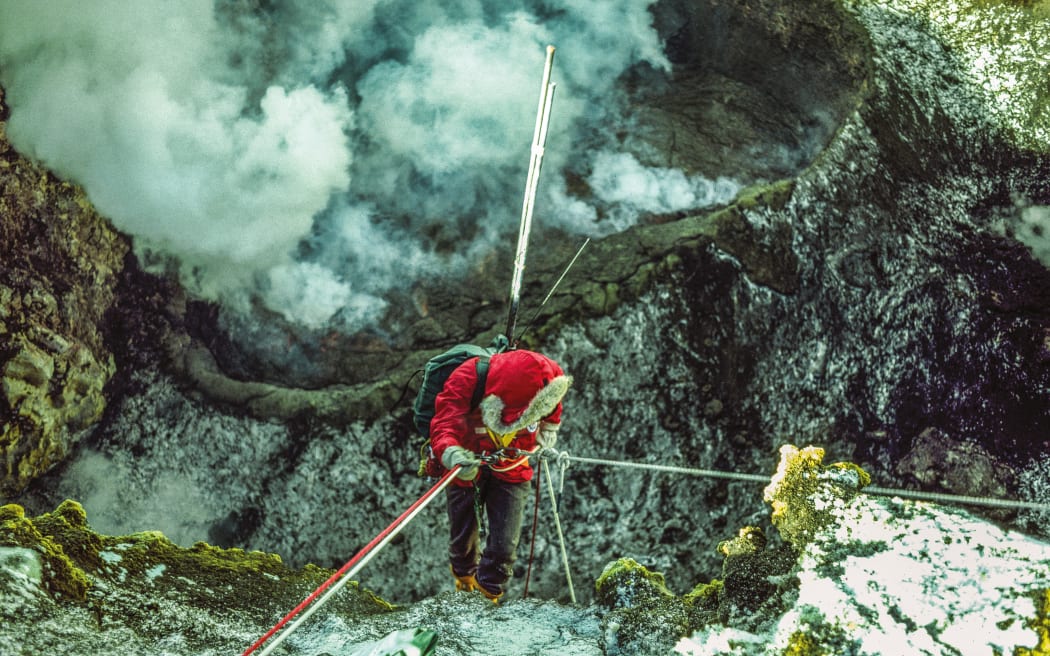 Werner Giggenbach abseils over the lip of the Inner Crater to commence an 80-metre drop towards the lava lake and fumaroles to take gas samples. Titanium rods stick out from his pack, used to
get a sampling flask close to hot escaping gas. COLIN MONTEATH