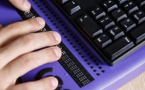 Blind person using computer with braille keyboard. Visual impairment, independent life concept.