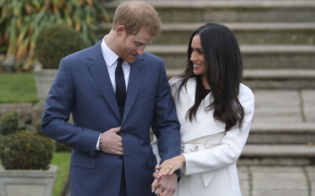 Britain's Prince Harry stands with his fiancée US actress Meghan Markle as she shows off her engagement ring at Kensington Palace in west London.