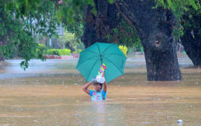 Residents of Korociri settlement cross through the flooded Nadi backroad in Fiji.