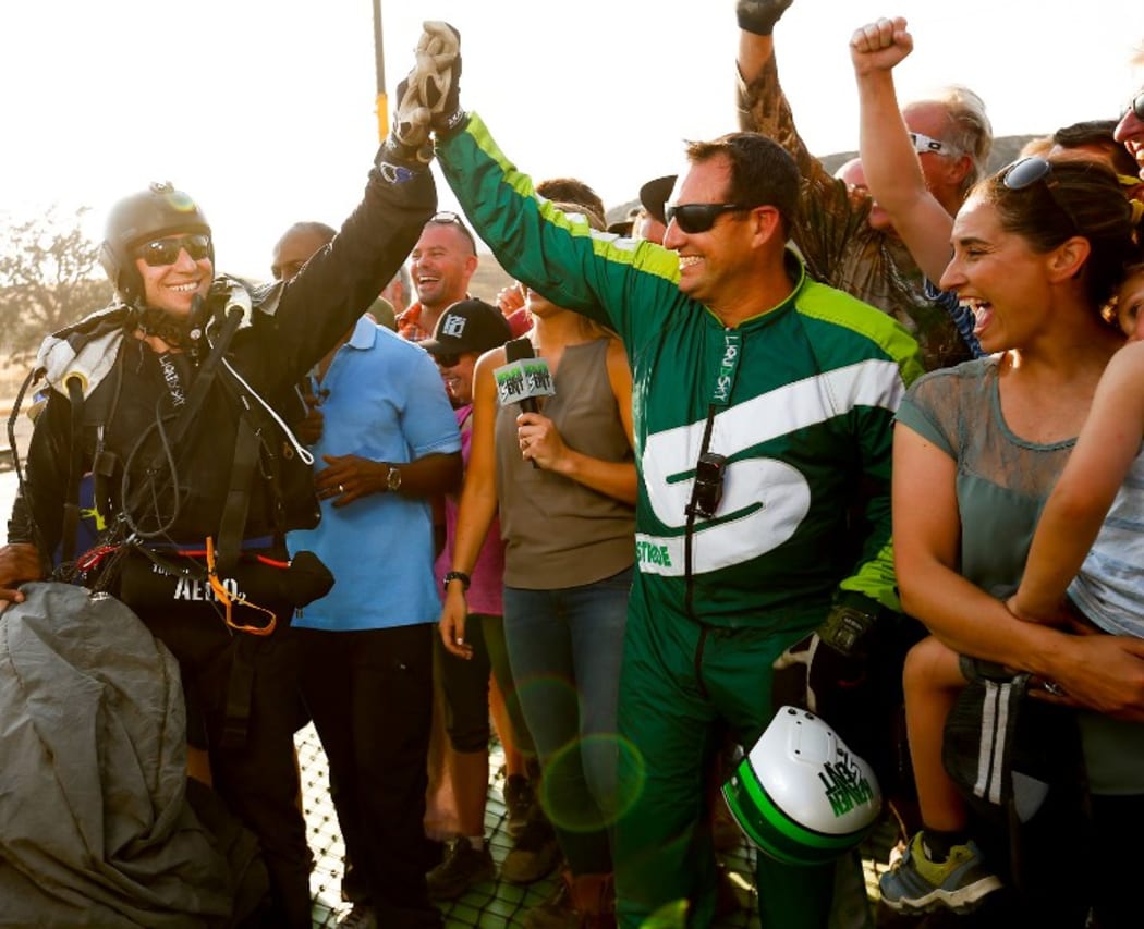 Skydiver Luke Aikins (right) celebrates after landing safely.