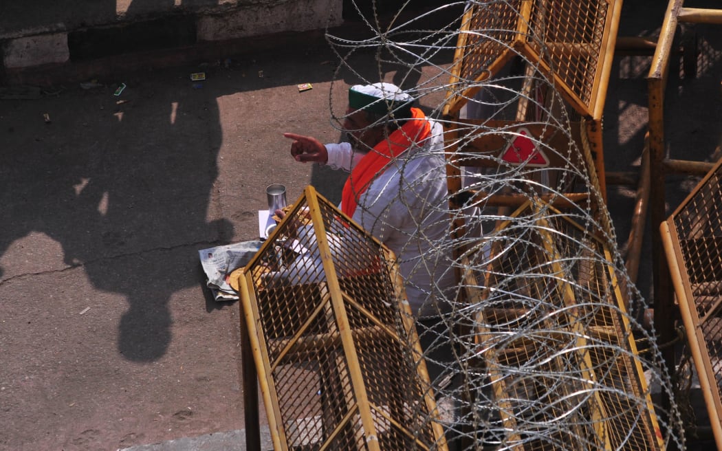 Bharatiya Kisan Union leader Rakesh Tikait eats lunch near police barricades during farmer's protest at Delhi - Gazipur road border , on 2 February 2021.
