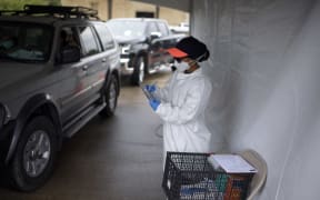 A healthcare worker takes information as cars line up at a Covid-19 testing site in Houston, Texas, 25 June 2020.