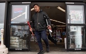 A man leaves a hardware store after purchasing the last two snow shovels the store had left, ahead of a winter storm in Quincy, Massachusetts on February 22, 2026. A fast-developing storm is threatening to pummel the US East Coast with a foot or more of snow beginning Sunday, bringing Mother Nature's wrath to a region that only just dug out from a previous winter wallop. Meteorologists issued blizzard warnings for New York and parts of at least six states, warning Saturday that heavy snow and gale-force winds are forecast to slam all major cities along the densely populated Interstate 95 northeast corridor, including Philadelphia, Boston and even Washington further south. (Photo by Joseph Prezioso / AFP)