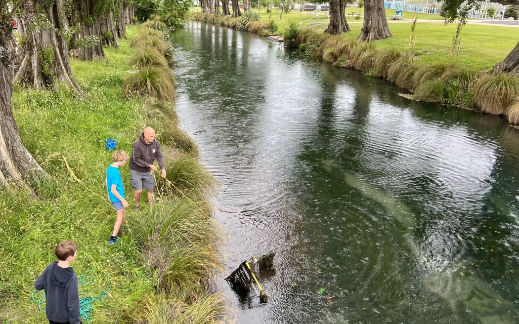 Tim Riley and his sons reeling in a shopping trolley at the Avon River.