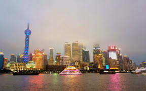 Tall buildings and night time lights of Shanghai from across the water.