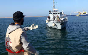 A Libyan Red Crescent worker awaits the arrival of a ship carrying African migrants at a naval base in Tripoli on 25 November 2017, after their rubber boat was rescued off the coast of Garabulli.