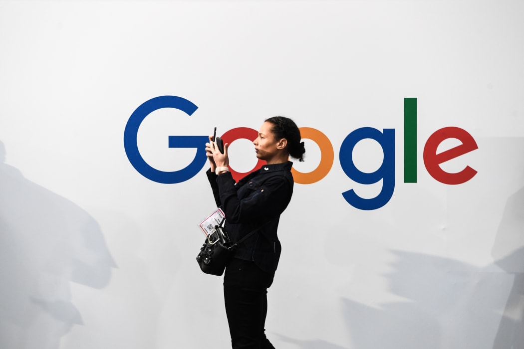 A woman takes a picture with two smartphones in front of the logo of the US multinational technology and Internet-related services company Google as he visits the Vivatech startups and innovation fair, in Paris on May 16, 2019.