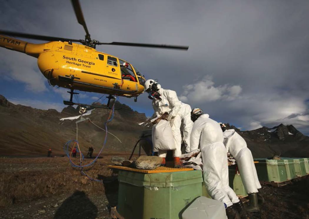 The very last bag of rat bait is loaded into the spreader bucket under Peter Garden’s helicopter Alpha Mike, at 12.37pm on 23rd March 2015