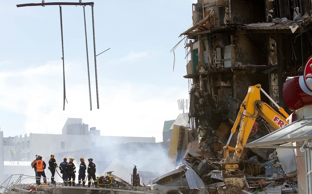 Rescuers stand at the smoking ruins of the CTV building, where 115 people died, in Christchurch on 24 February, 2011, two days after the deadly earthquake.