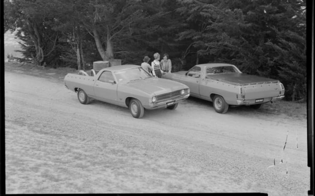 People talking next to two Ford Falcon utes (pick up truck),