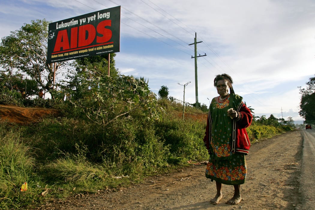 A woman walks past a HIV/AIDS billboard in PNG