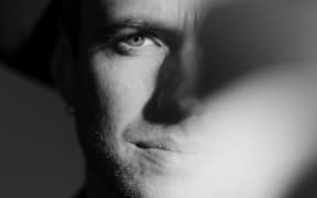 Black and white close up of Finn's face, partially obscured by a blurred light.