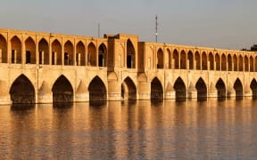This picture taken on May 15, 2022 shows a view of the 295-metre-long "Si-o-Se Pol" (33 arches) bridge, completed in 1596 during the reign of the Safavid Shah Abbas, along the Zayandeh Rood (river) in Iran's central city of Isfahan. The famed river bridges of the Iranian city of Isfahan are a beloved tourist draw -- but on most days their stone arches span just sand and rocks, not water. Drought and upstream water diversions have seen the Zayandeh Rood, "fertile river" in Persian, run dry since 2000, with only rare exceptions. (Photo by ATTA KENARE / AFP)