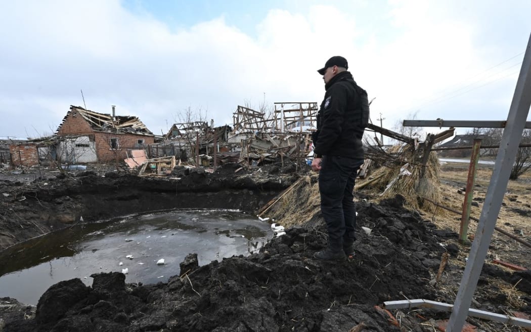 A policeman examines a crater after Russian shelling in Vovchans'k, Kharkiv region, on March 9, 2023. (Photo by SERGEY BOBOK / AFP)