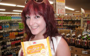 Scarlett, in a market, holding a package of "candy cheese"