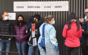 A medical worker (C) speaks to people queueing outside a COVID-19 coronavirus testing venue at The Royal Melbourne Hospital in Melbourne on July 16, 2020.