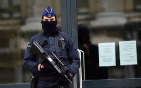 An armed policeman stands guard at the entrance of Belgium's federal prosecutor office in Brussels.