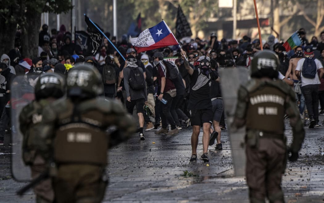 Demonstrators clash with riot police in Santiago, Chile, during protests against the government's economic policies