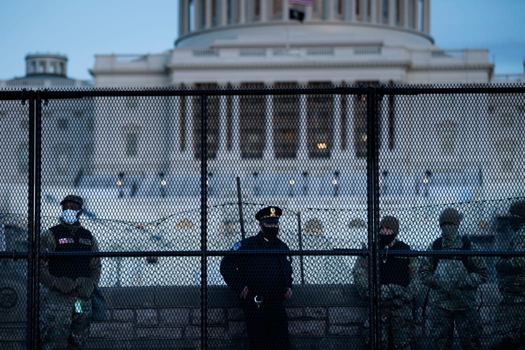 A Capitol Police officer stands with members of the National Guard behind a crowd control fence surrounding Capitol Hill a day after a pro-Trump mob broke into the US Capitol on January 7, 2021, in Washington, DC.