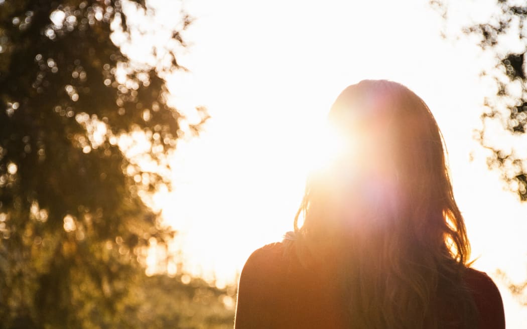 Rear view of silhouetted mid adult woman gazing over mountain forest at sunset, Palomar, California, USA (Photo by Yew! Images / Connect Images / Connect Images via AFP)