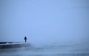 A man walks along Lake Michigan at sunrise amid sub-zero temperatures on December 22, 2022 in Chicago, Illinois.
