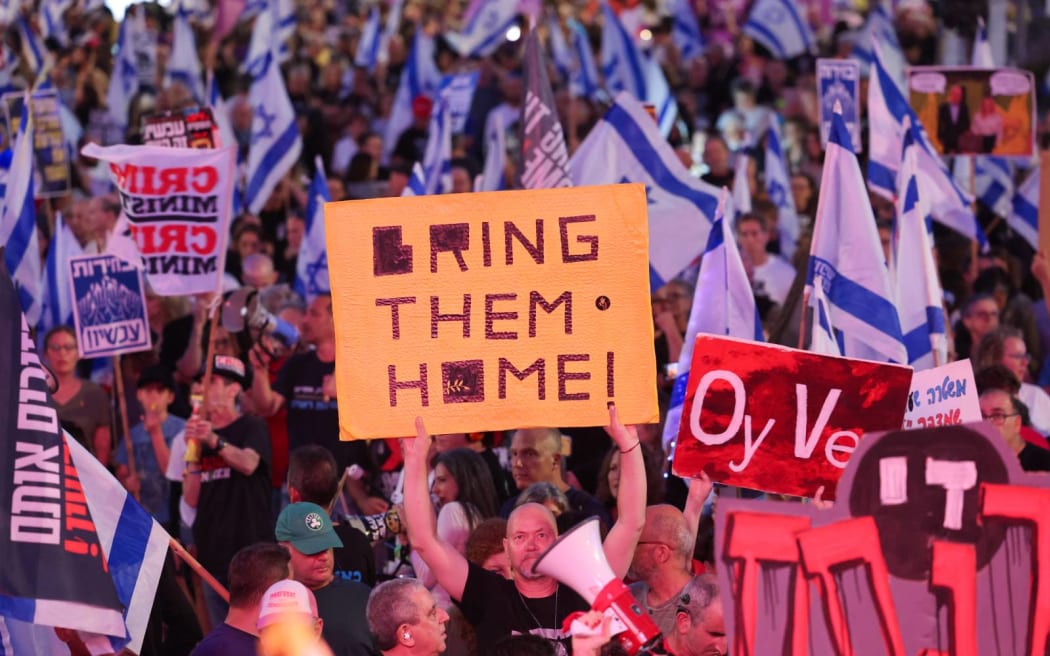Israeli left-wing activists wave national flags and hold placards during an anti-government demonstration in Tel Aviv, on May 4, 2024, amid the ongoing conflict in the Gaza Strip between Israel and the Palestinian militant Hamas movement. (Photo by JACK GUEZ / AFP)