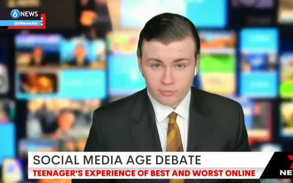 Leo is seated for a live interview with a green screen of a busy newsroom behind him. He wears a suit and has AirPods in to hear the presenter.