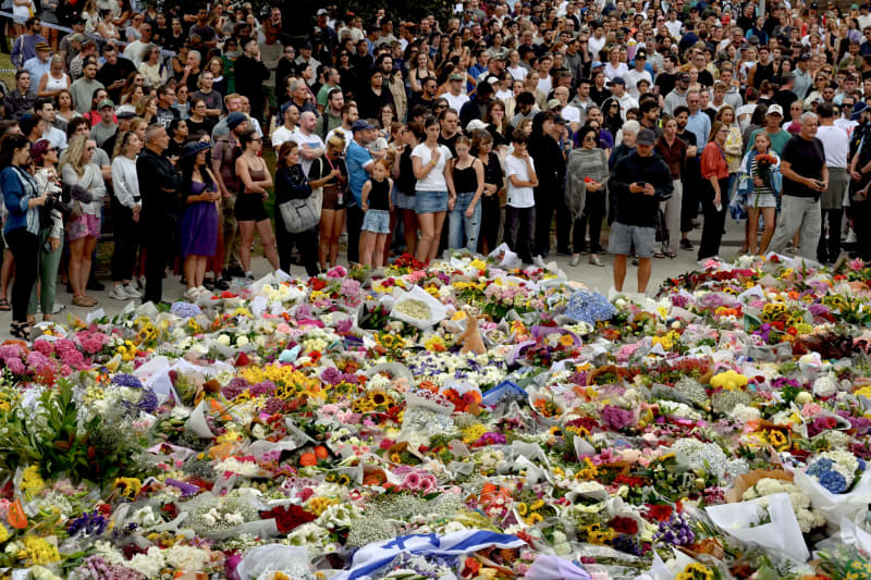Mourners gather by floral tributes at the Bondi Pavillion in memory of the victims of a shooting at Bondi Beach, in Sydney on December 15, 2025. A father and son opened fire on a Jewish festival at Australia's Bondi Beach in a shooting spree that killed 15 people, including a child, authorities said on December 15, denouncing the attack as antisemitic "terrorism". (Photo by Saeed KHAN / AFP)