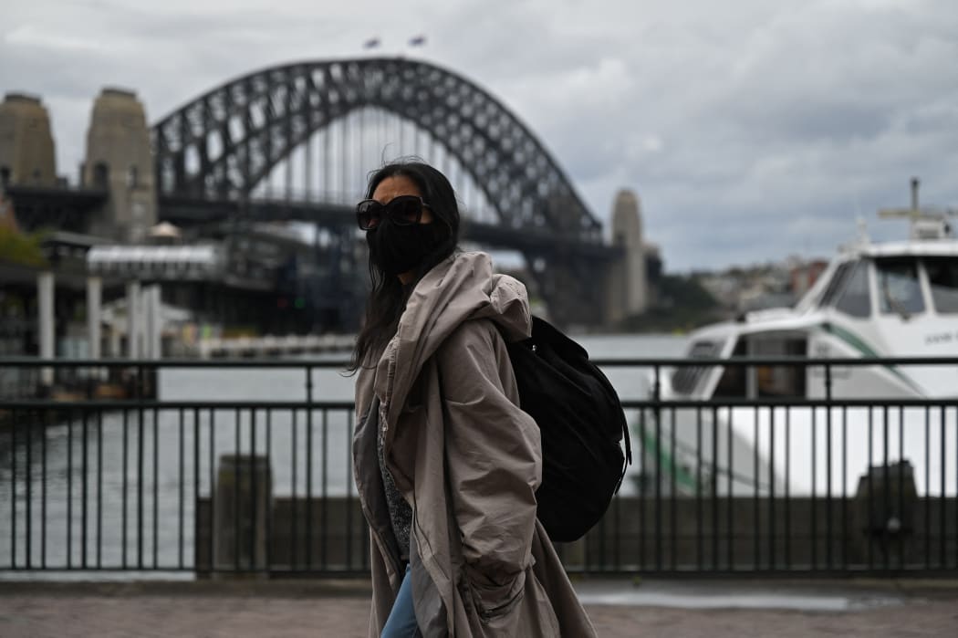 A woman walks past the Sydney Harbour Bridge after stay-at-home orders were lifted across NSW.