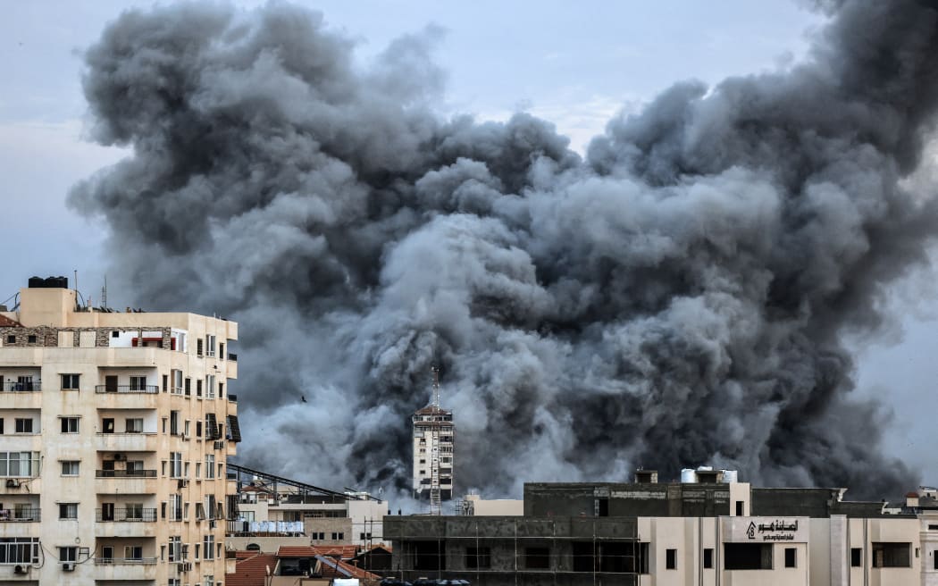 A plume of smoke rises above buildings in Gaza City on October 7, 2023 during an Israeli air strike. At least 70 people were reported killed in Israel, while Gaza authorities released a death toll of 198 in the bloodiest escalation in the wider conflict since May 2021, with hundreds more wounded on both sides. (Photo by MAHMUD HAMS / AFP)