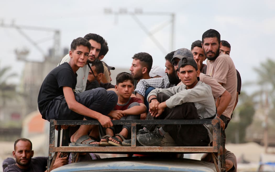 Displaced Palestinians ride on top of a vehicle in the south of Deir el-Balah in the central Gaza Strip on October 6, 2025. Delegations from Hamas, Israel and the United States are holding talks in Egypt on October 6, with President Donald Trump urging negotiators to "move fast" to end the nearly two-year war in Gaza. (Photo by Bashar TALEB / AFP)