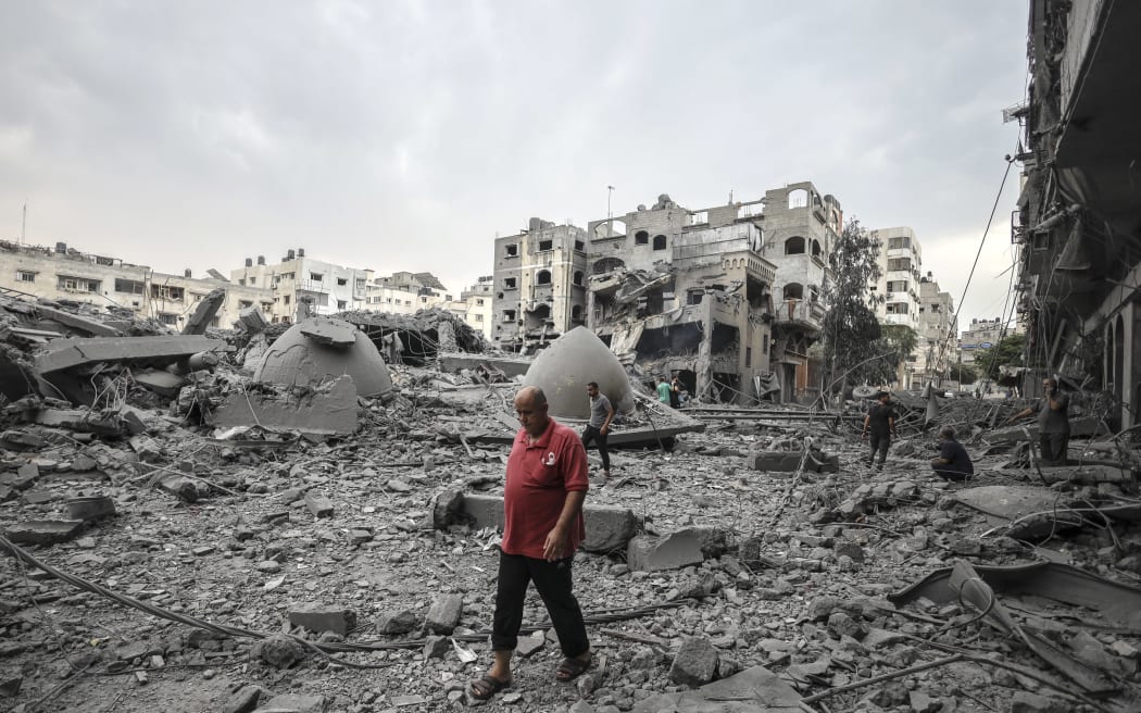 A Palestinian  man walks in front of the rubble of destroyed buildings and mosque after an Israeli air strikes in Gaza City, on October 9, 2023.