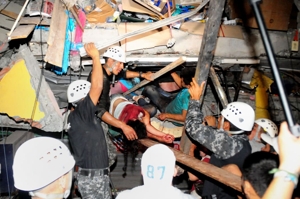 Rescue workers work to pull out people trapped in a building in Manta.