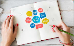 Image of someone writing in a book with multiple words for 'hello'