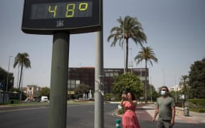 A couple take a photo of a street thermometer reading 48 degrees Celsius during a heatwave in Cordoba on August 13, 2021. - Temperatures are forecast to reach highs of around 40 degrees Celsius (104 degrees Fahrenheit) in much of Spain and neighbouring Portugal. (Photo by JORGE GUERRERO / AFP)
