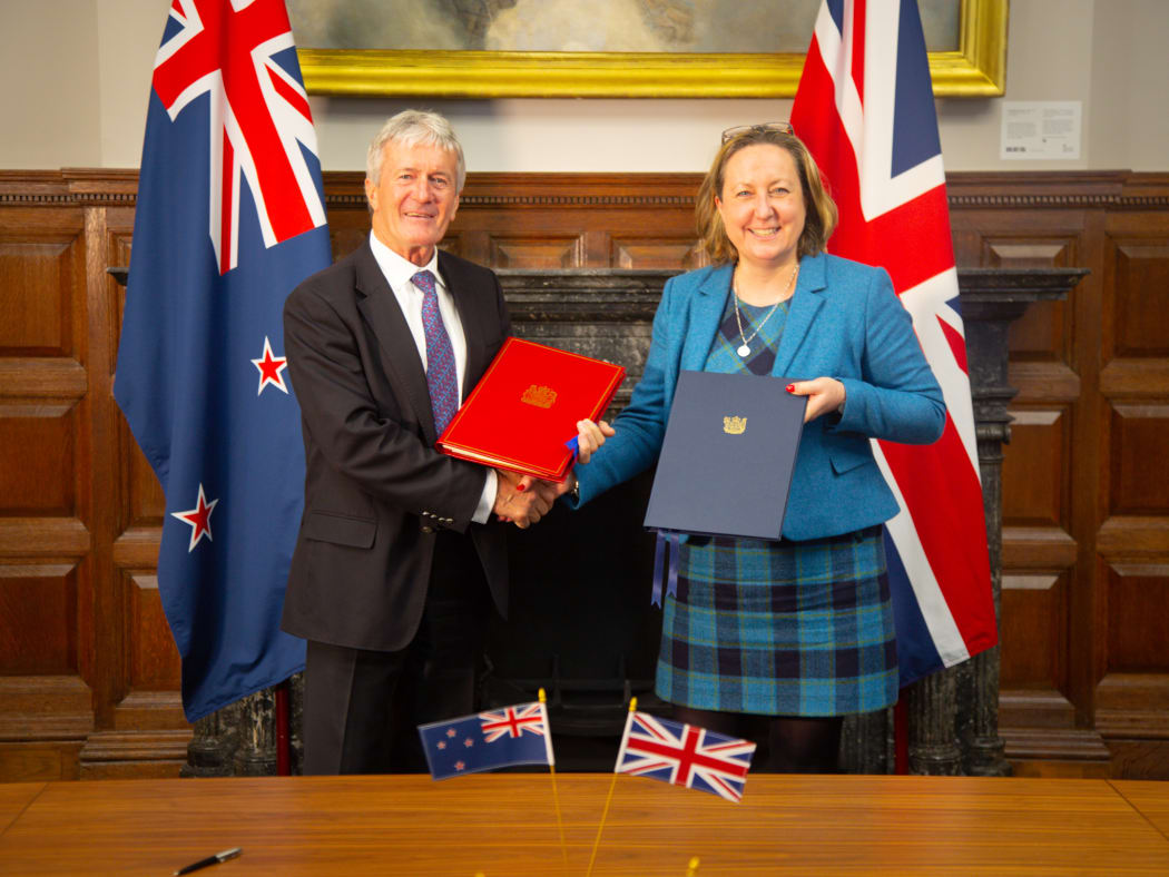 A man and a woman hold folders and shake hands.