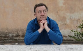 Musician Matthew Bannister looking pensive while leaning on a wall