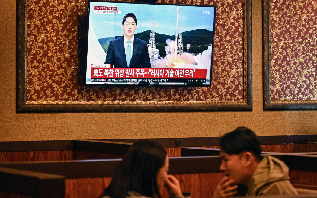 TOPSHOT - Customers sit near a television showing a news broadcast at a restaurant in Seoul on November 21, 2023, after North Korea fired what it claims is a military spy satellite, Seoul's armed forces said on November 21, hours after Japan confirmed that Pyongyang had warned it of an imminent launch. (Photo by Anthony WALLACE / AFP)