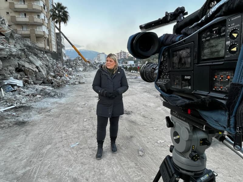 Correspondent Lisette Reymer standing in the rubble for a morning live cross after a night of camping out in a car amid constant earthquake aftershocks in Turkey.