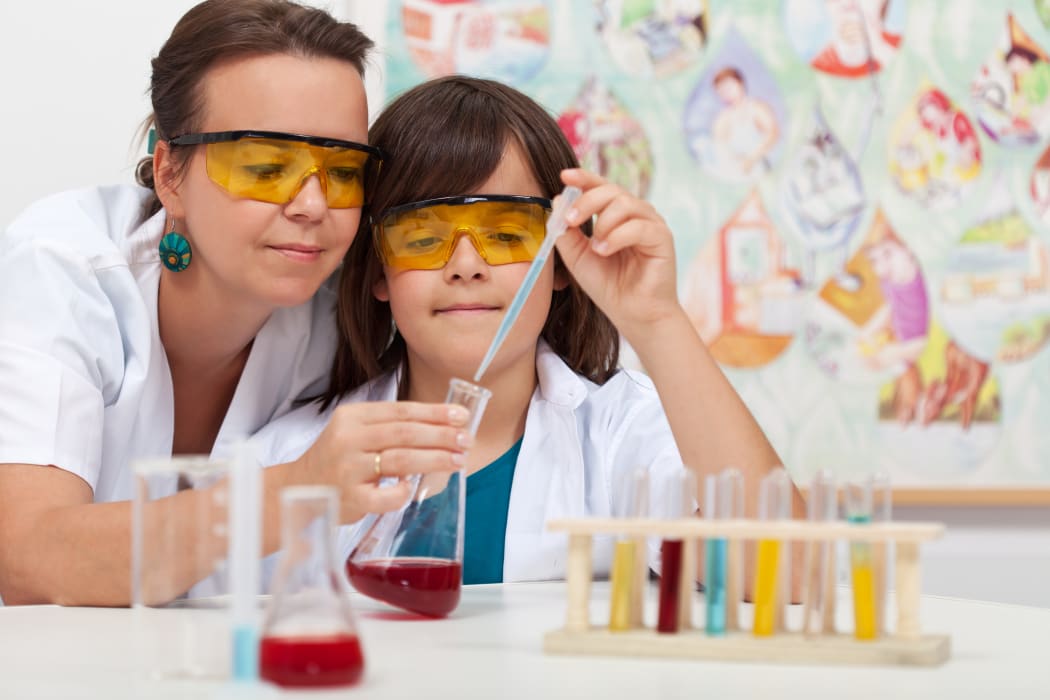 A file photo shows a primary school student being helped by a teacher in a school chemistry lab.
