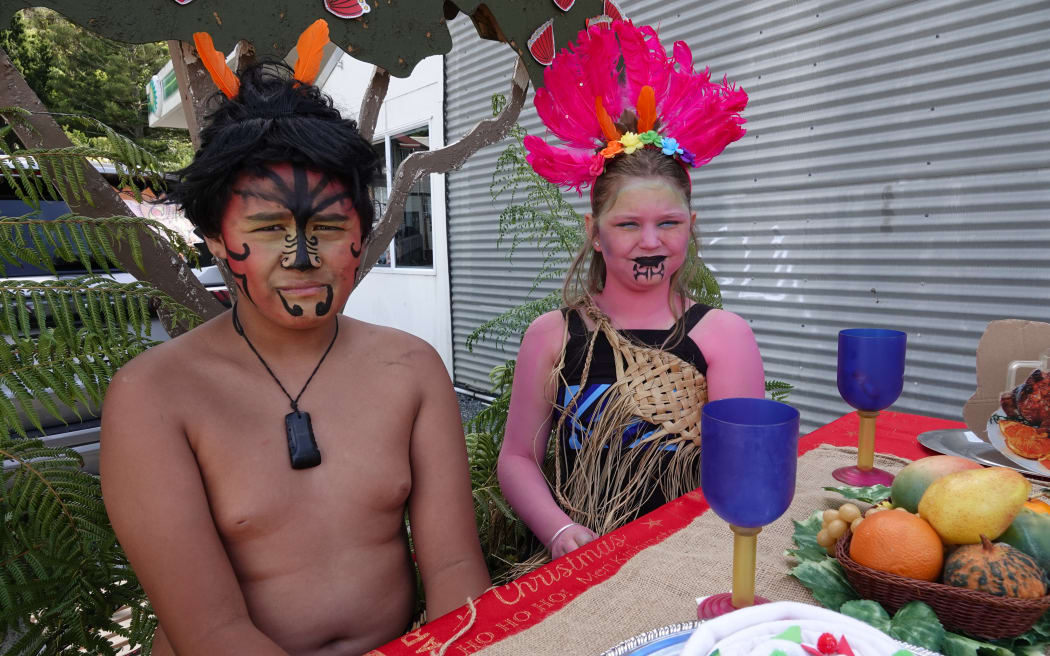 Ngakau Hansen, 11, as Tamanuiterā, and Eva Candy, 10, as Hineraumati, share a feast on the Kāeo Primary School float.