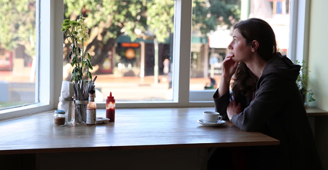 A picture of Pip Howells looking pensive alone in a cafe