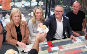 Australia's re-elected Prime Minister Anthony Albanese receives his coffee alongside his partner Jodie Haydon (2nd L) at a cafe in Sydney on May 4, 2025, following his party’s decisive victory in the federal election. (Photo by DAVID GRAY / AFP)
