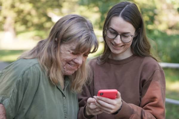 Camille and Hayley looking at Miles on the phone and smiling.