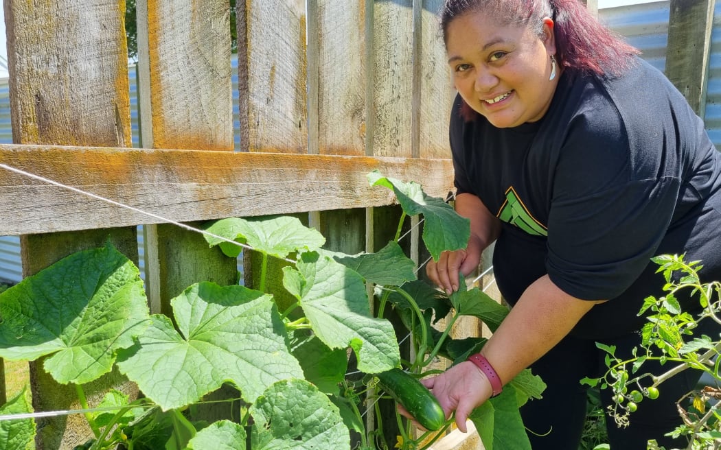 Te Rina Waiwiri shows a cucumber growing in her garden.